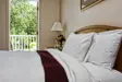 Bed in a hotel room with a terrace view of trees