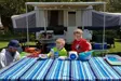 Family at picnic table with camper in the background