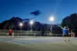 People playing tennis on court at night