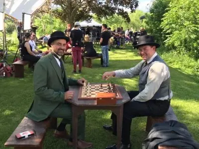 Two actors playing chess at a table 